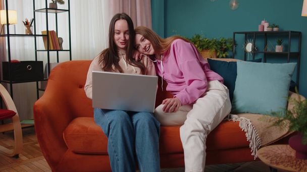 Young adult women couple looking at laptop notebook screen making online shopping purchase at home - Foto, immagini