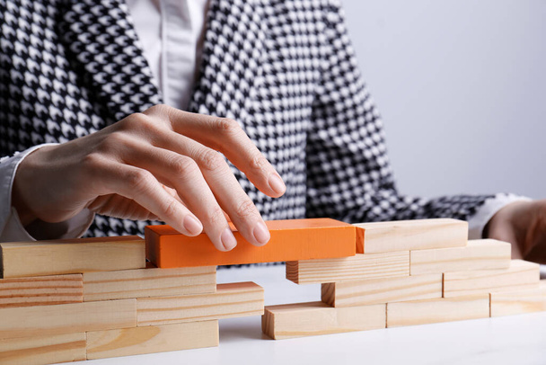 Businesswoman building bridge with wooden blocks at table, closeup. Connection, relationships and deal concept - Photo, Image