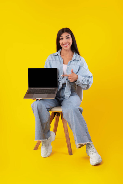 Happy woman pointing at black empty laptop screen - Foto, Bild
