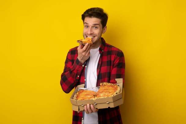 Happy Guy Holding Box mordiendo pizza en el estudio - Foto, Imagen