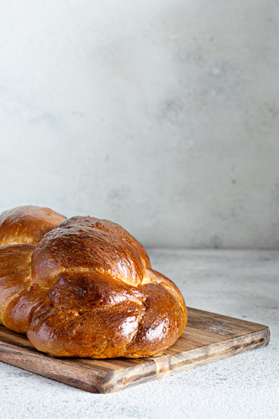 Challah o Hala es un tradicional pan trenzado (pan) de sábado fresco y dulce judío, pan fresco en la tabla de cortar. Brioche en la mesa de desayuno.  - Foto, Imagen