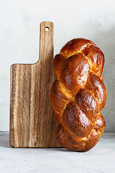 Challah ή Hala είναι ένα παραδοσιακό εβραϊκό γλυκό φρέσκο Σάββατο Πλέκεται ψωμί (καρβέλι), φρέσκο ψωμάκι σε ξύλο κοπής. Brioche στο τραπέζι του πρωινού.  - Φωτογραφία, εικόνα