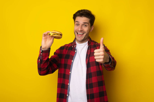 Divertente ragazzo holding hamburger mostrando pollice su - Foto, immagini