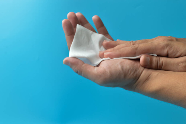 Otírání rukou pomocí bílé papírové tkáně izolované na modrém pozadí. Hygiena, bezpečnost a koncepce zdravotní péče. - Fotografie, Obrázek