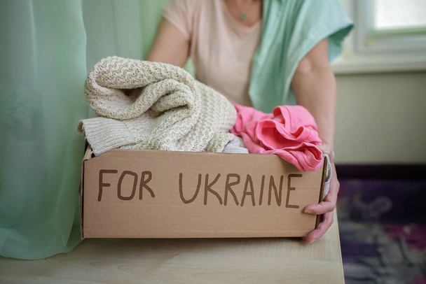 Kobieta trzyma pudełko z pomocą humanitarną dla obywateli Ukrainy cierpiących na inwazję rosyjską - Zdjęcie, obraz