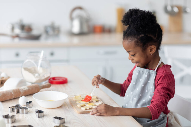 Adorable little black girl making cookies, side view - Foto, imagen