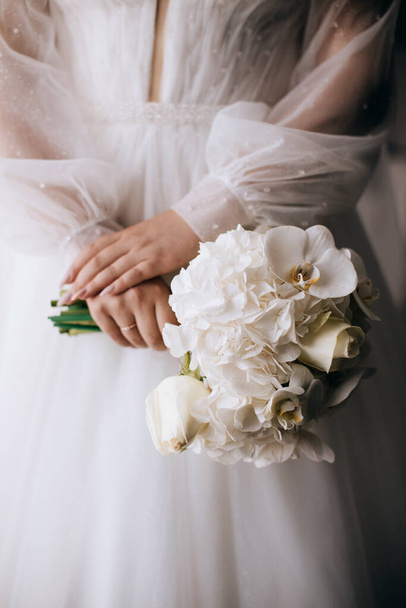 The bride holds an elegant bouquet of white orchids. Wedding morning - Foto, afbeelding