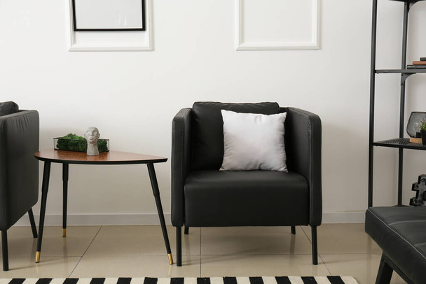 Stół z ozdobnym mchem i czarnym fotelem przy ścianie - Zdjęcie, obraz