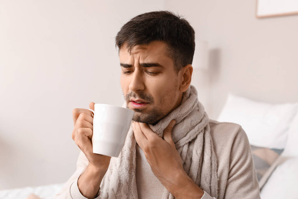 Ill young man with sore throat drinking hot tea at home - Photo, Image