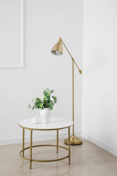 Table moderne avec plante d'intérieur et lampe à l'intérieur de la pièce lumineuse - Photo, image