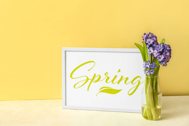 Ramka ze słowem SPRING i pięknymi wiosennymi kwiatami na stole - Zdjęcie, obraz