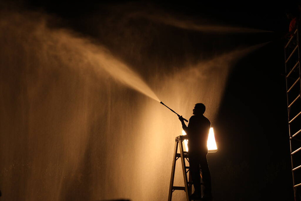 Silueta de bombero con boquilla de manguera de fuego - Foto, Imagen
