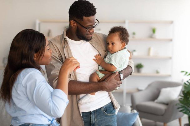 Feliz negro padres sosteniendo bebé y jugando - Foto, Imagen