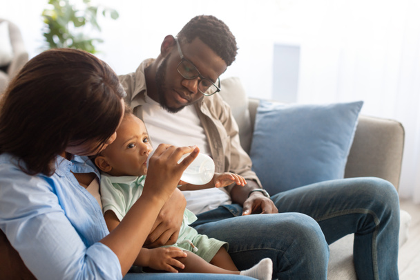 Giovani genitori afroamericani che allattano il bambino dalla bottiglia - Foto, immagini