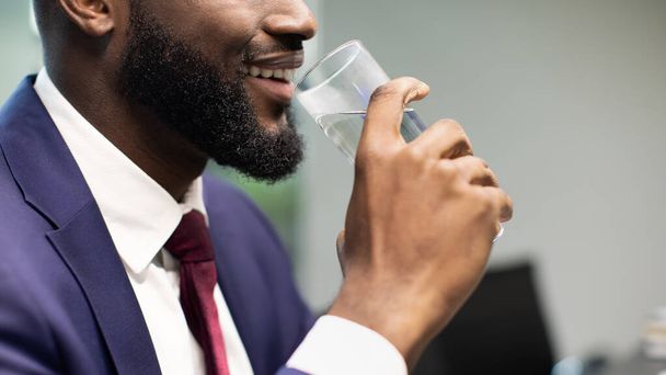 Unrecognizable black businessman drinking water, copy space - Фото, изображение