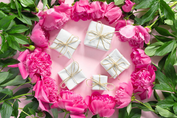 Bouquet of beautiful pink peonies with gift boxes in paper wrapping. Round frame of flowers. Background for text. - Foto, imagen