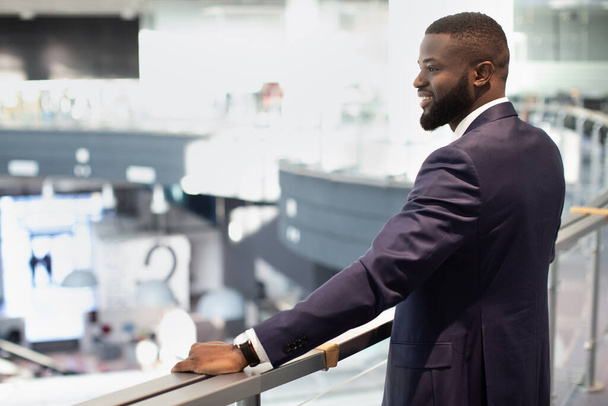 Веселий афроамериканський молодий бізнесмен дивиться на свій офіс
 - Фото, зображення