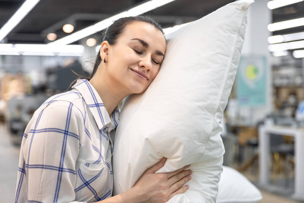 A young woman chooses a pillow in a home improvement store. - Fotoğraf, Görsel