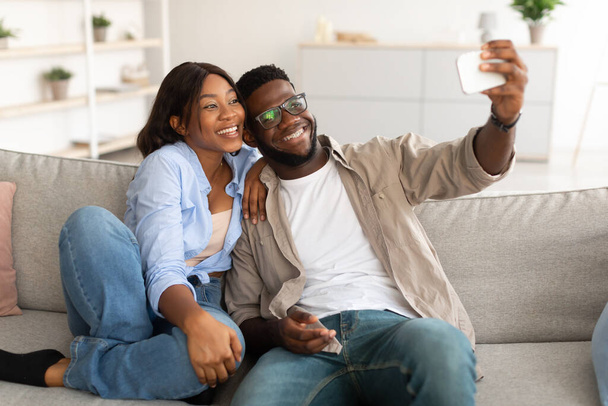 Portrait of happy black couple taking selfie together at home - Fotó, kép