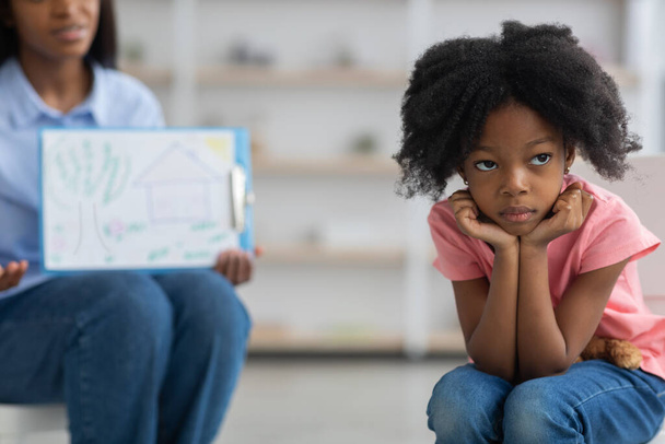 Gelangweiltes kleines Mädchen meidet unkenntliche Kinderpsychologin - Foto, Bild