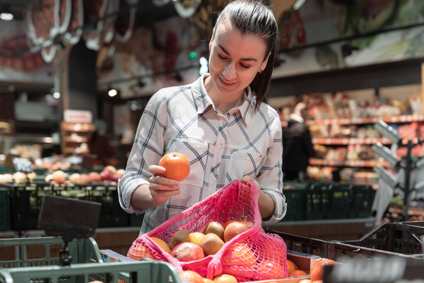 A young woman chooses fruits in a supermarket. - Foto, Bild