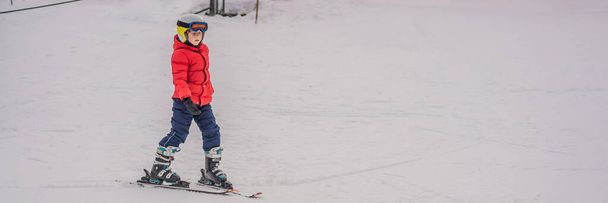 BANNER, LONG FORMAT Ski pour enfants en montagne. Enfant tout-petit actif avec casque de sécurité, lunettes et bâtons. Course de ski pour jeunes enfants. Sport d'hiver pour la famille. Cours de ski pour enfants à l'école de ski alpin. Peu - Photo, image