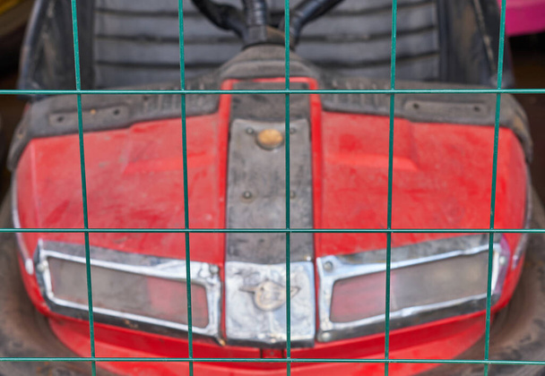 voiture rouge d'une attraction pour enfants derrière une clôture en treillis - Photo, image