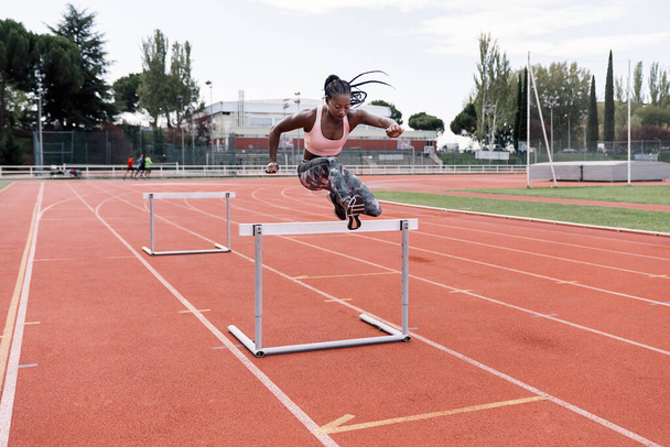 African-American athlete sprinter jumping a hurdle - Foto, afbeelding