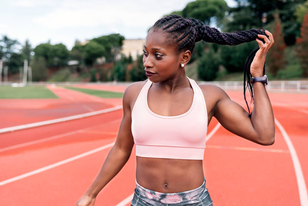 Athlete sprinter touching braided hair - Valokuva, kuva