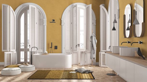 Salle de bain moderne dans des tons jaunes dans un appartement classique avec fenêtre cintrée. Baignoire autoportante, lavabos, miroirs, tapis, étagère avec serviettes et peignoir. Design intérieur minimaliste - Photo, image