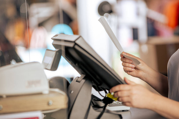 Jeune femme qui traite le paiement avec la facture ou la facture sur le terminal de caisse POS dans la boutique, concept de finance - Photo, image