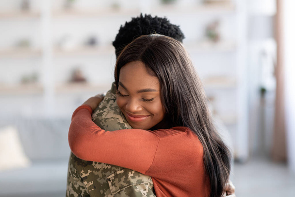 Reunion Concept. Bella donna nera felice che abbraccia il marito militare a casa - Foto, immagini