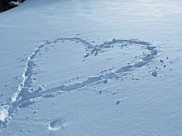 Lodowate serce śniegu - ślady świeżego alpejskiego śniegu w kształcie serca na zboczach pasma górskiego Alpstein, Unterwasser - Kanton St. Gallen, Szwajcaria (Schweiz) - Zdjęcie, obraz