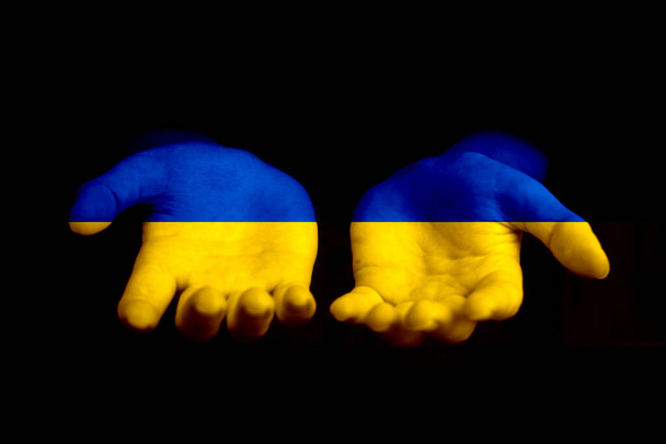Arrêtez la guerre. Ukraine drapeaux sur les jeunes mains, fond noir. Concept de paix - Photo, image