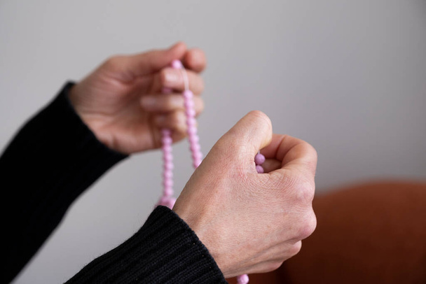 Nahaufnahme muslimische Frau die Hand hält rosa Rosenkranz, um für Gott zu beten.Muslim Gottesdienst zu Hause. - Foto, Bild