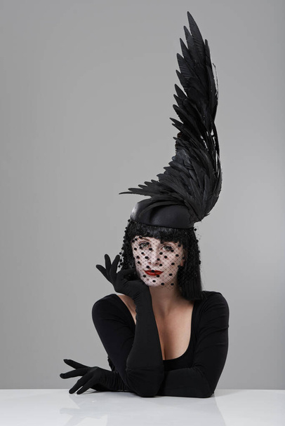 Es braucht alles Mögliche. Aufnahme einer jungen Frau mit einer flügelförmigen Kopfbedeckung in einem Atelier. - Foto, Bild