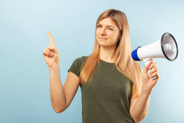 青い背景にメガホンを持つ若い女性。スピーチの概念と発表、マーケティングや販売のアイデア. - 写真・画像