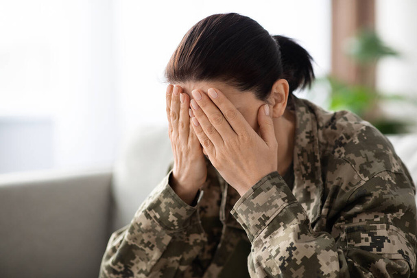 Στρατιωτική ψυχική υγεία. Στρατιώτης γυναίκα κάθεται στον καναπέ, καλύπτει το πρόσωπο σε απόγνωση - Φωτογραφία, εικόνα