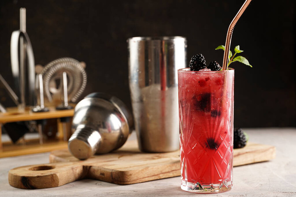 Yksi pitkä lasi alkoholittomalla mocktail versio klassinen karhunvatukka ja gin cocktail bramble puulaudalla, cocktail laitteet - Valokuva, kuva