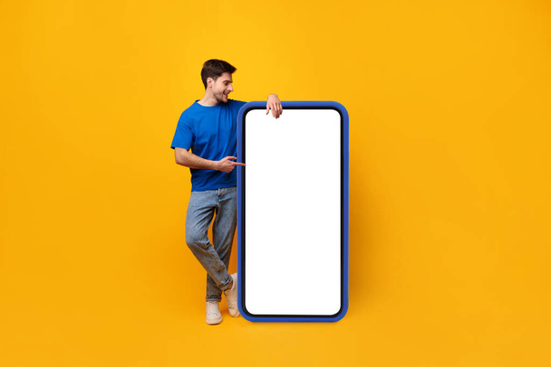 Guy pointing and leaning on big white empty smartphone screen - Φωτογραφία, εικόνα