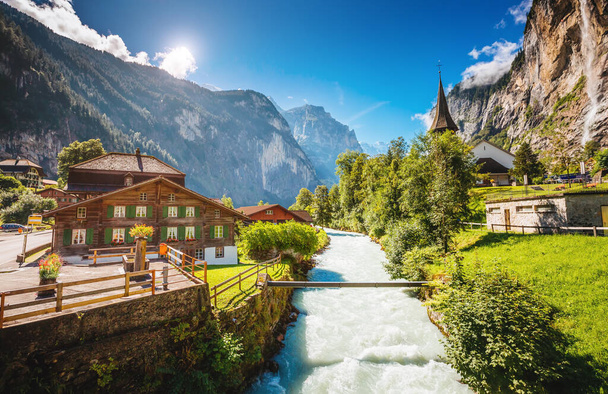 Μαγευτική θέα του αλπικού χωριού που λάμπει από το φως του ήλιου. Γραφική και πανέμορφη σκηνή. Τοποθεσία διάσημο μέρος Ελβετικές Άλπεις, Lauterbrunnen Valley, καταρράκτη Staubbach, Ευρώπη. Καλλιτεχνική φωτογραφία. Ομορφιά κόσμος - Φωτογραφία, εικόνα