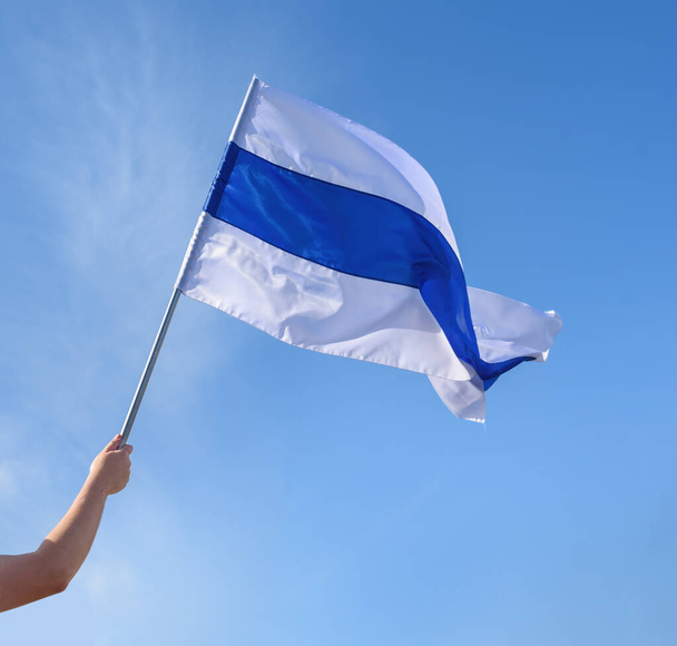 Ruka držící bílo-modrobílou vlajku používanou ruskými protiválečnými demonstranty proti ruské invazi na Ukrajinu v roce 2022 - Fotografie, Obrázek