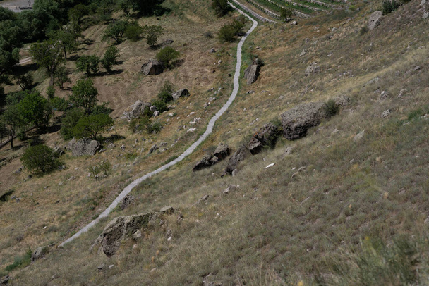 Скалистые горы Грузии с зелеными кустами по краям и небольшая дорога между ними - Фото, изображение