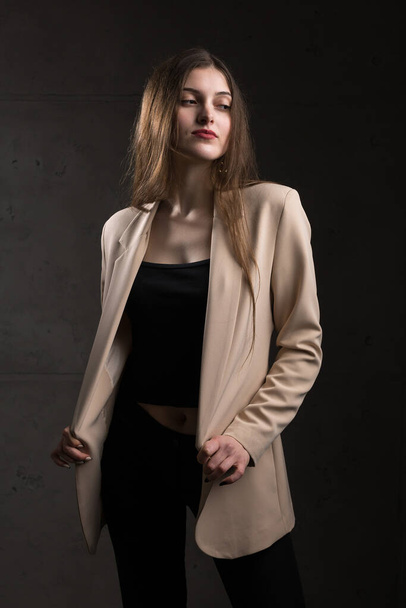 Portrait of a young brunette with long hair in the studio. Dramatic photo in dark colors. - Foto, Imagem