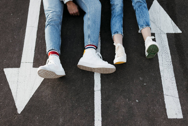 Unrecognizable young couple sitting between the signs on the floor of a skate park - Photo, image