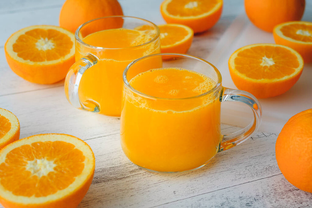 Arance e succo d'arancia spremuto fresco da vicino su fondo di legno chiaro - Foto, immagini