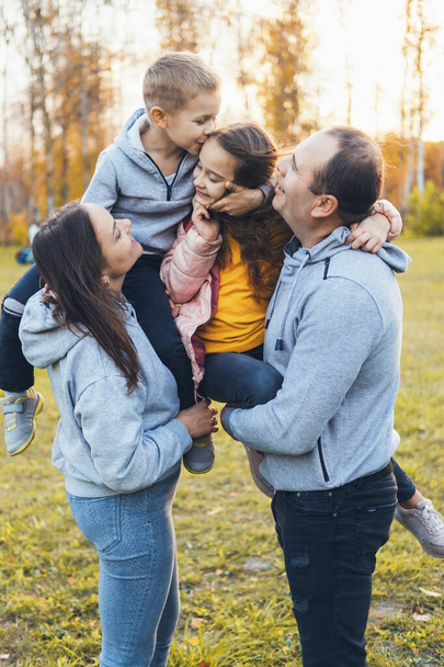 Parents with two children spending time together and having fun while walking through the park in the fall. Smiling happy child. Happy family together. - Photo, Image