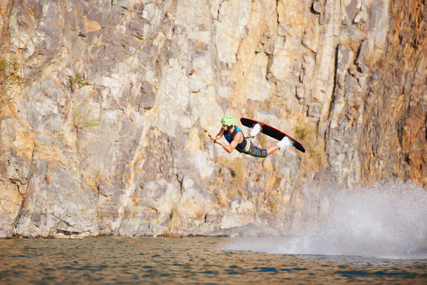 Um jovem usando um elmo e colete salva-vidas wakeboarding em um lago. Um jovem usando um capacete e colete salva-vidas wakeboarding em um lago. - Foto, Imagem