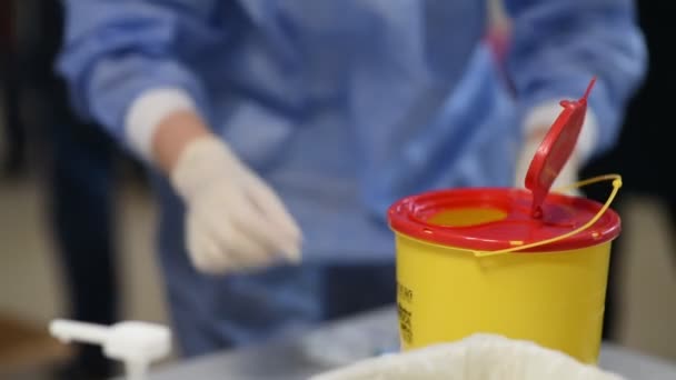 Ο γιατρός πετάει μια χρησιμοποιημένη σύριγγα και ιατρικά απόβλητα σε ένα πλαστικό δοχείο - Πλάνα, βίντεο