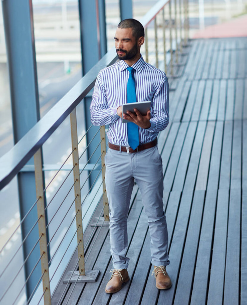 La technologie rapproche les affaires de lui. Prise de vue d'un jeune homme d'affaires utilisant une tablette numérique à l'extérieur d'un immeuble de bureaux. - Photo, image